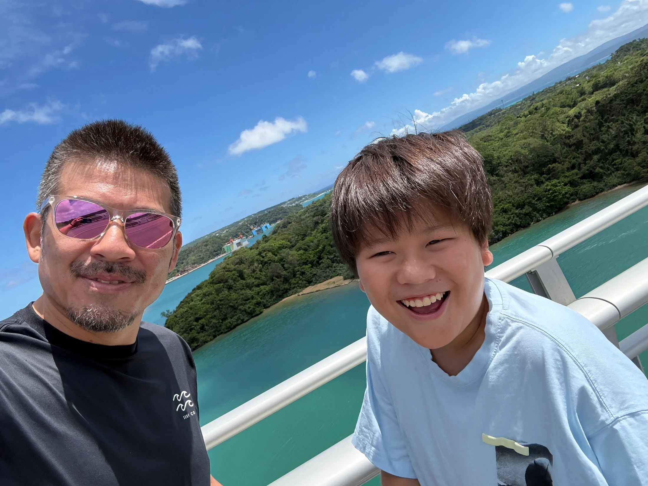 沖縄の青い海と空を背景に、笑顔で並ぶパパとツバ