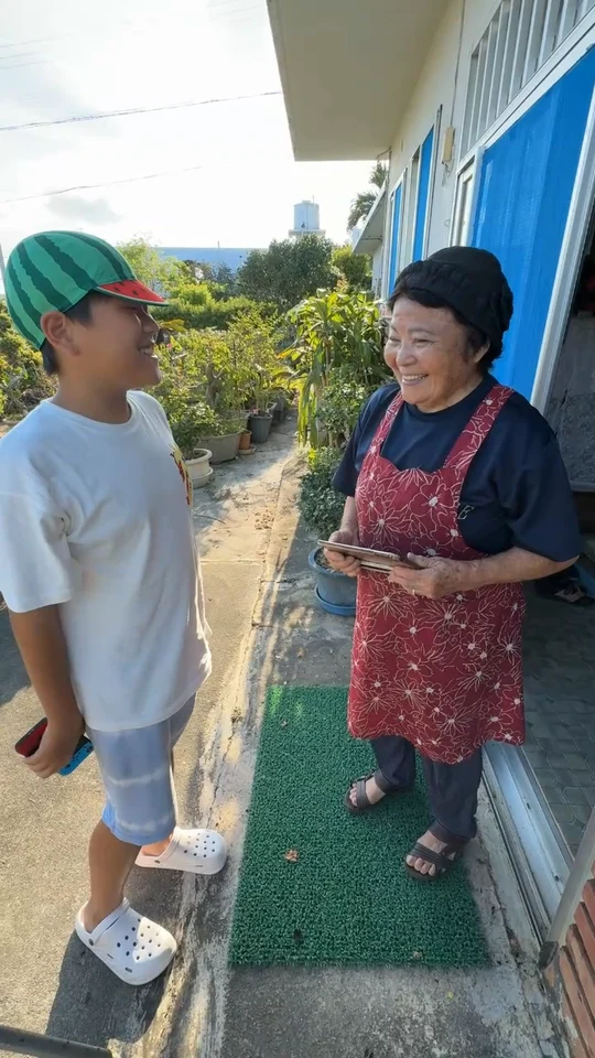 伊江島の民家の前で、笑顔で向き合うツバとおばあちゃん